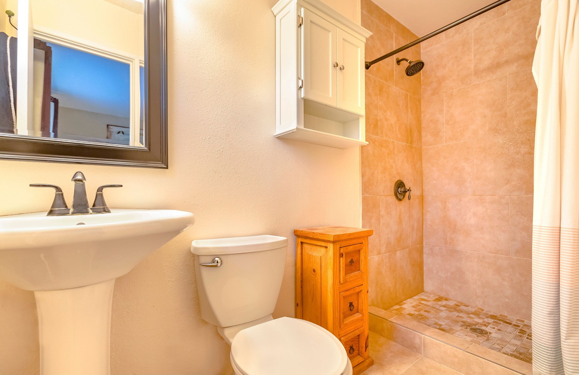 Modern clean and open bathroom in California home downstairs with side table and wall cabinet